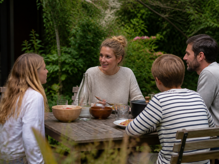 Famille assise autour table bois dans jardin verdoyant