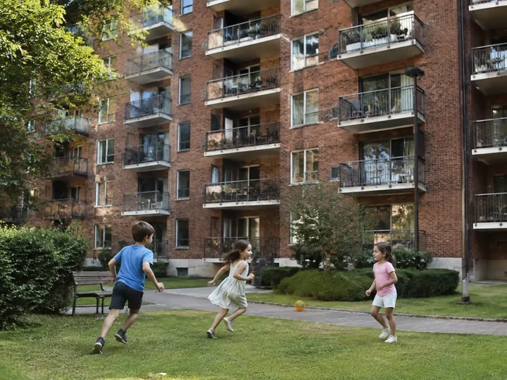 Grands immeubles en briques, balcons et enfants jouant devant