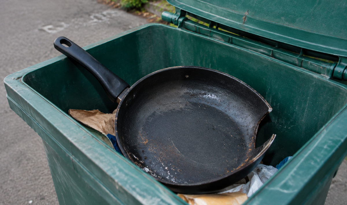 Poele noire endommagee posee dans bac recyclage ouvert