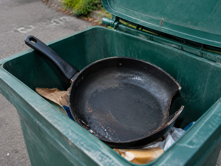 Poele noire endommagee posee dans bac recyclage ouvert